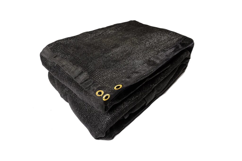 A folded black mesh tarp with two gold metal grommets is placed on a white background.