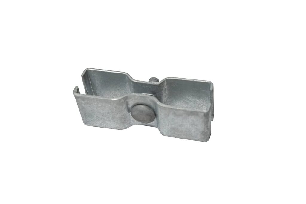 A close-up of a small, metallic bracket or connector, featuring a central circular indentation and two open ends, placed against a plain white background.